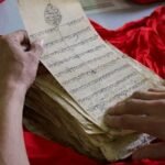 Hands examining an ancient script in Pune, India, showcasing cultural heritage.